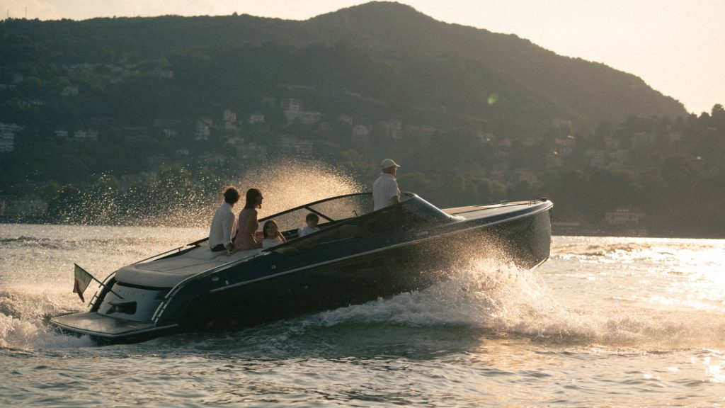 A family rides in a speedboat across sunlit water on Lake Como