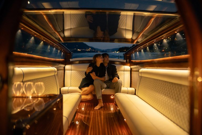 Couple sitting together in a luxury boat cabin at night on Lake Como